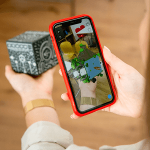 Ein Handy scannt einen Mergecube, auf dem Display sieht man eine Augmented Reality Darstellung