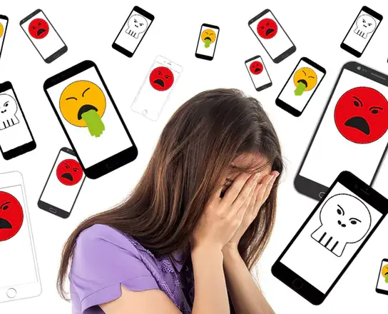 Mädchen verdeckt ihr Gesicht mit ihren Händen und ist von Handies mit bösen Emojies umgeben