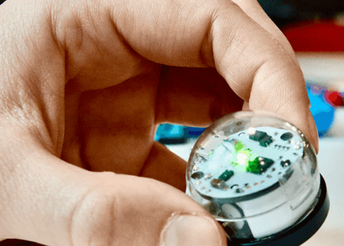 Ein Ozobot wird mit einer Hand festgehalten