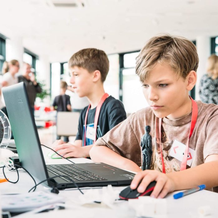 Zwei Jungen sitzen vor Laptops