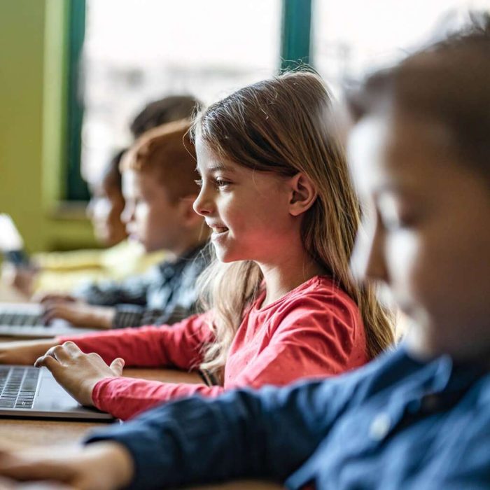 Kinder die in der Schule in einer Reihe sitzen