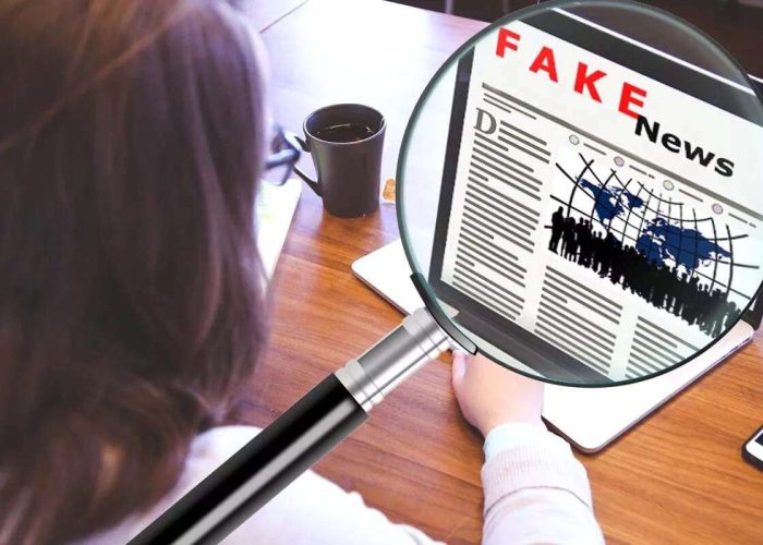 Weibliche Person an einem Laptop, auf den mit einer Grafik einer Lupe herangezoomt wird. Auf dem Bildschirm ist eine Zeitungsseite mit der Überschrift "Fake News" zu sehen.