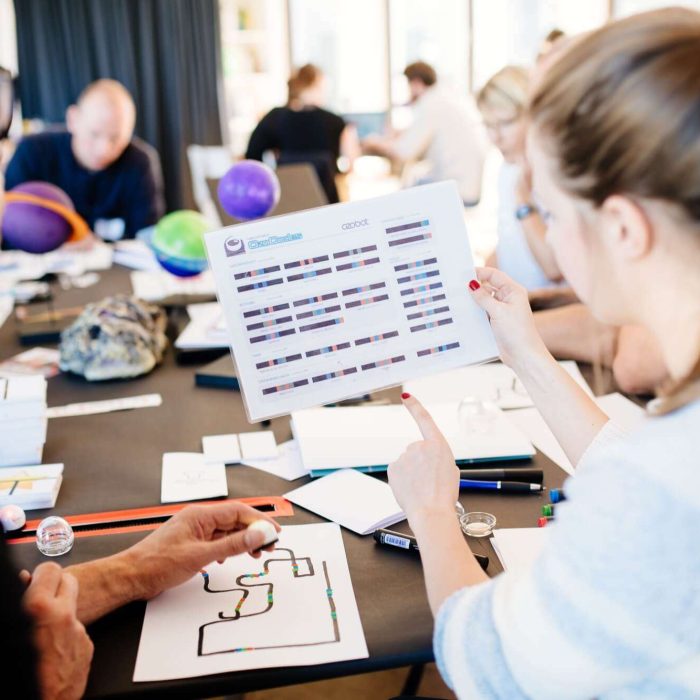 Ein Lehrer und eine Lehrerin schauen auf ein Arbeitsblatt des Ozobot-Roboters.