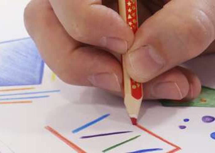 Kind zeichnet mit Buntstift auf Papier